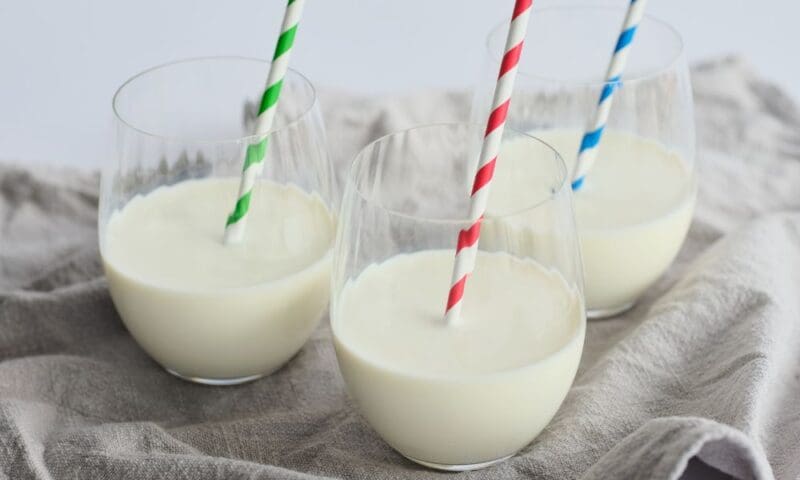 Three glasses of milk with a green, red and blue striped straw.